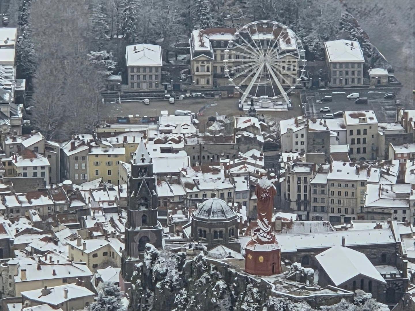 Grande roue installée dans une ville enneigée pour un marché de Noël